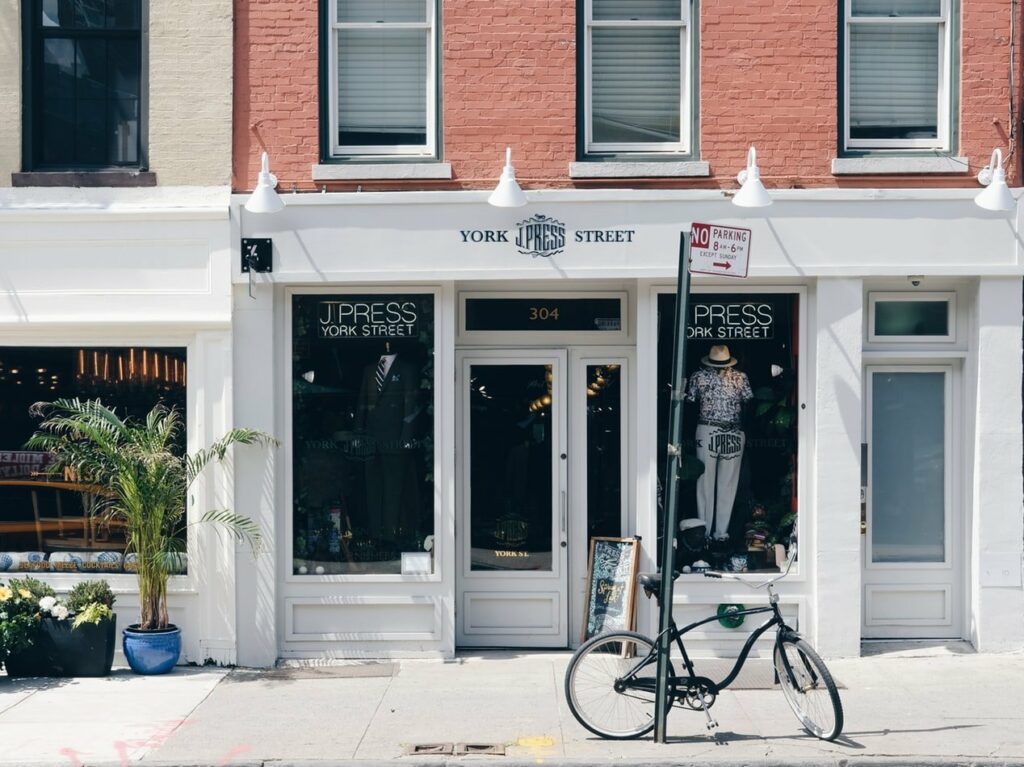 The image shows a modern storefront with a bright sign featuring "Web Design Services" and related keywords like SEO optimization, digital marketing agency, and branding strategy, illustrating their offerings.